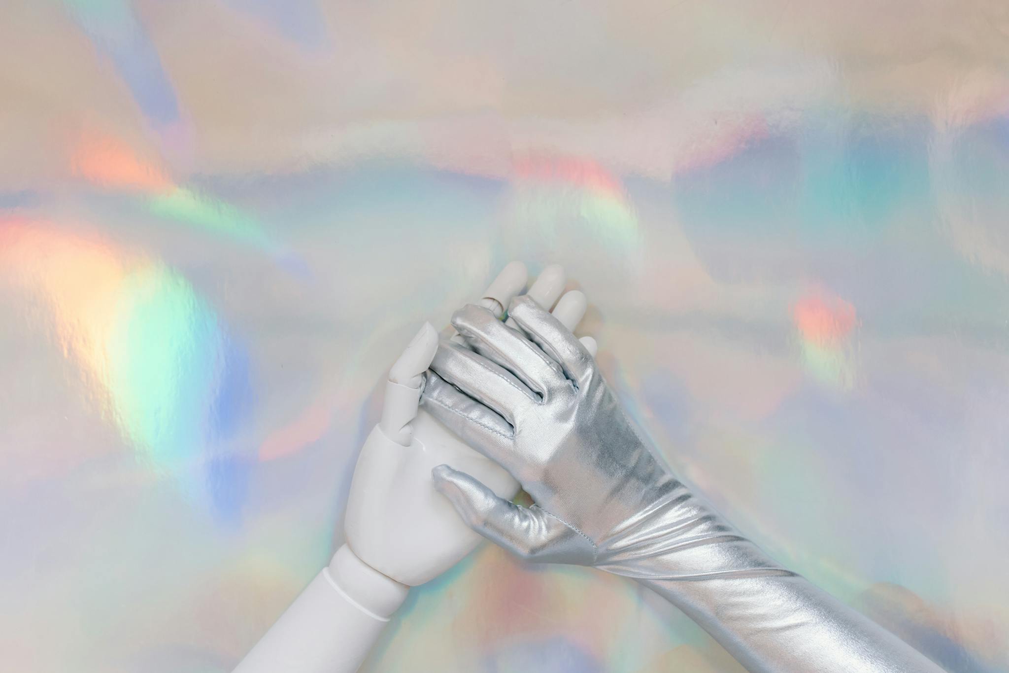 Close-up of a silver metallic glove on a colorful holographic background, evoking a futuristic theme.